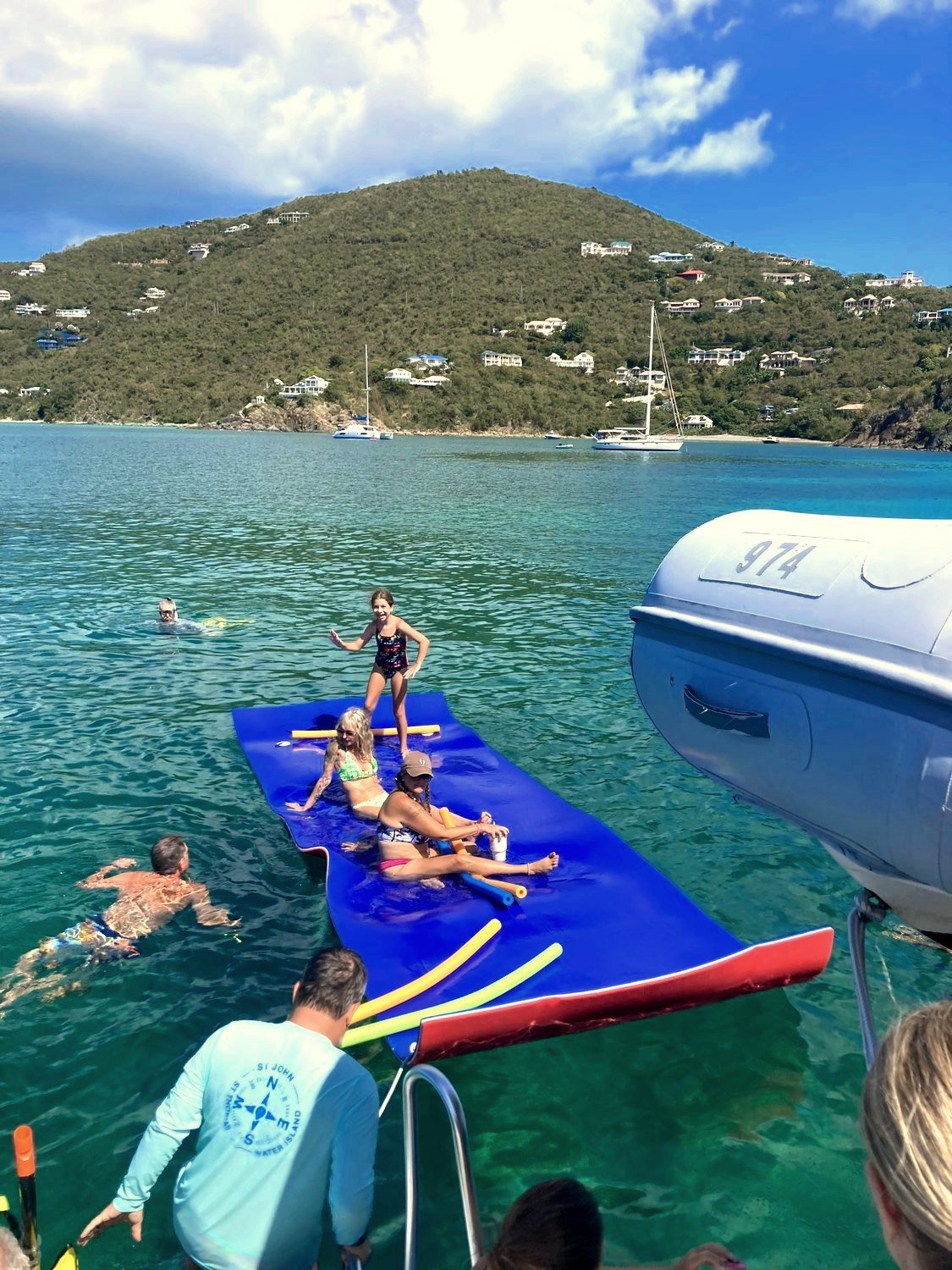 A family relaxing on a floating mat in calm turquoise water off St. John