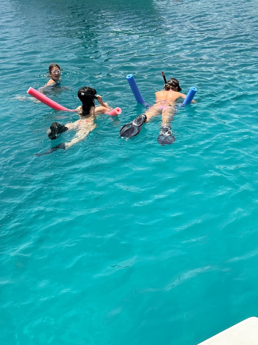 Three young guests snorkeling with pool noodles in clear turquoise Virgin Islands water