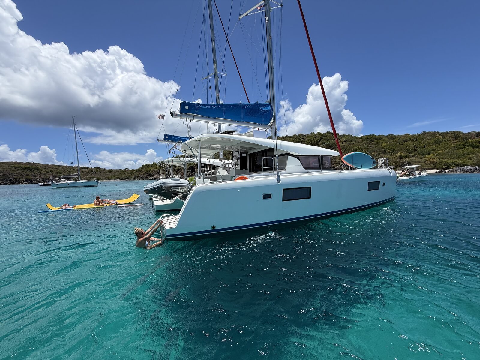 Sterns of Pau Hana and Kai Lana with guests on a yellow floating mat in clear turquoise water