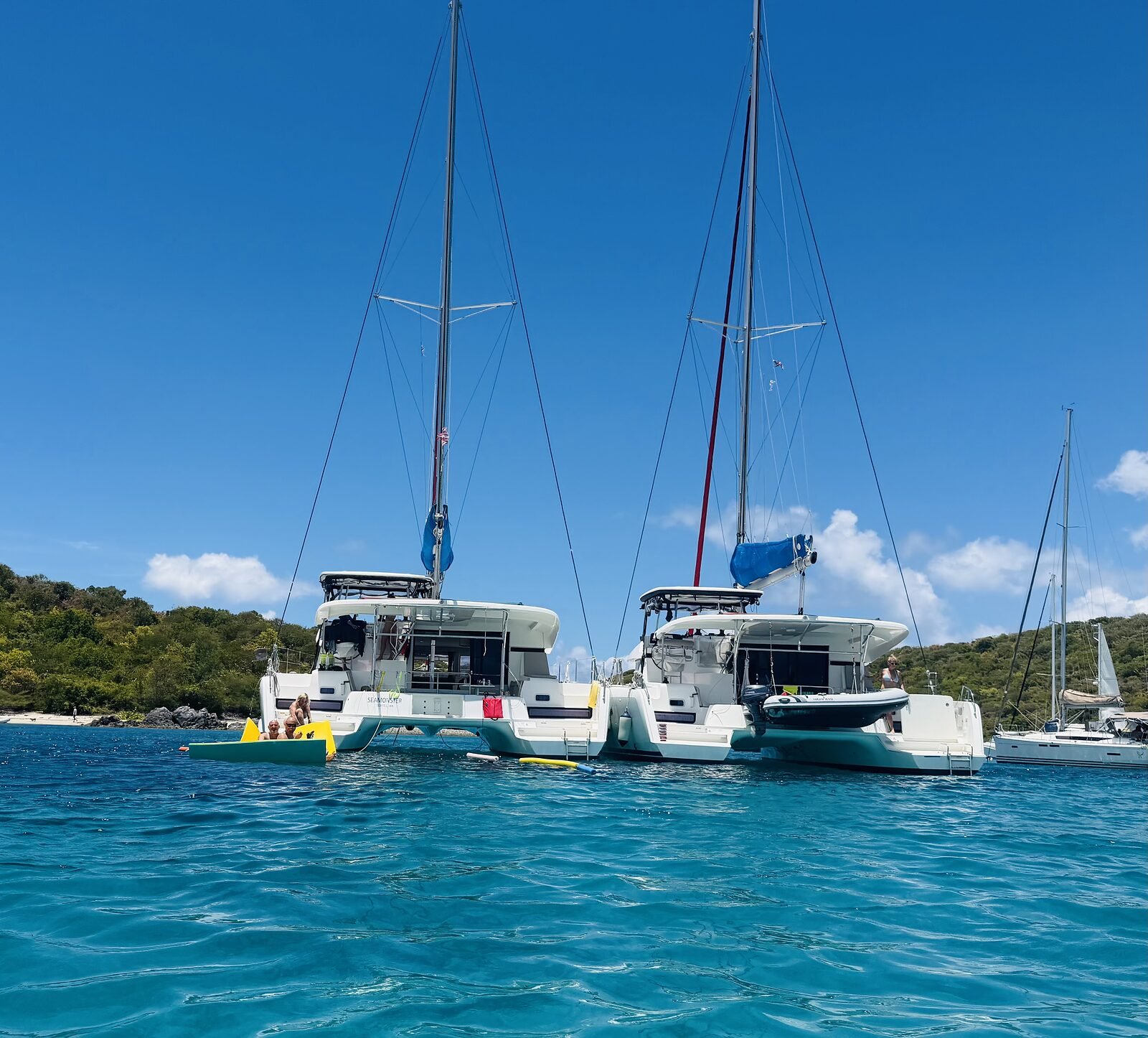 Close view of the rafted catamaran sterns with guests aboard