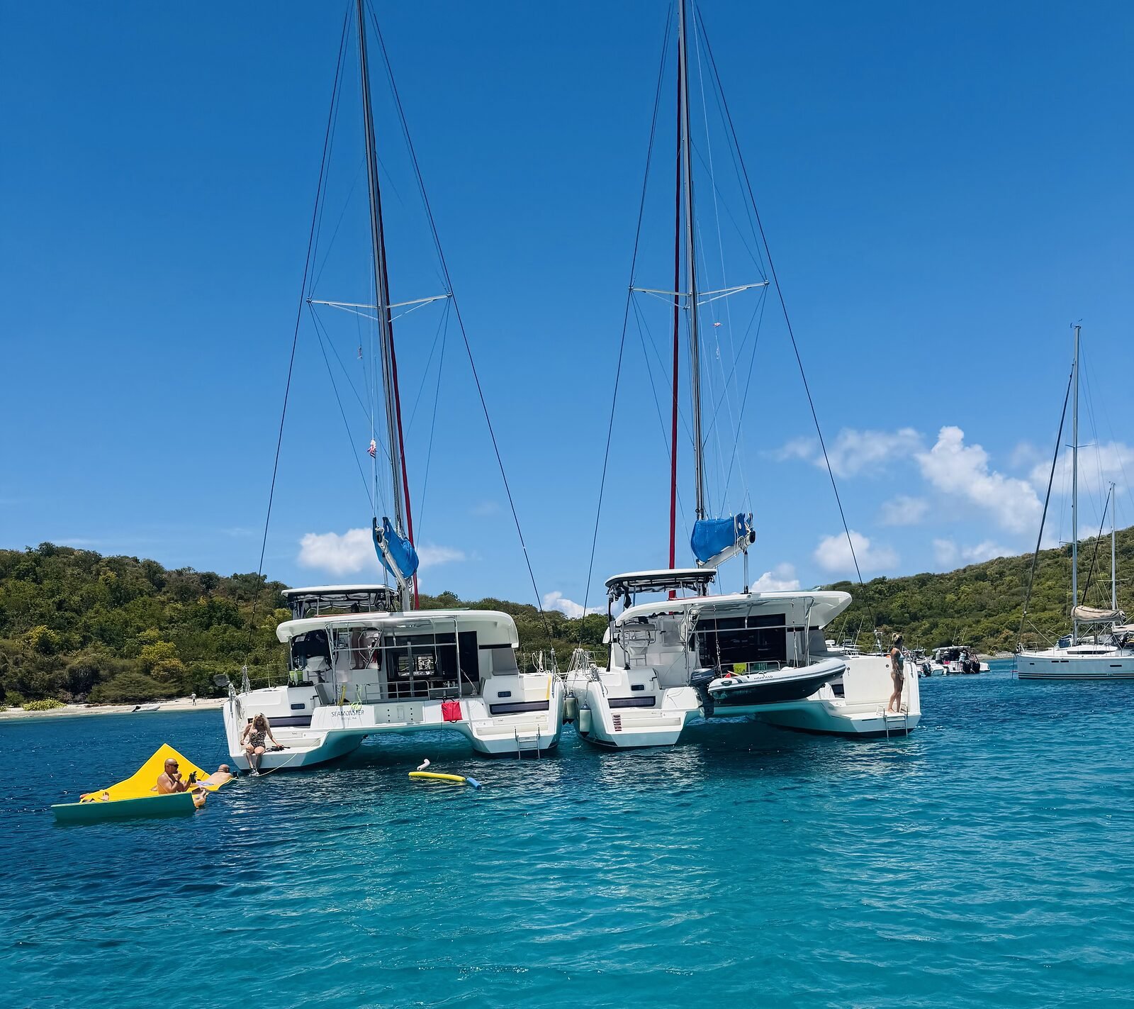 Close-up of Pau Hana and Kai Lana rafted together with guests aboard in a turquoise Virgin Islands anchorage