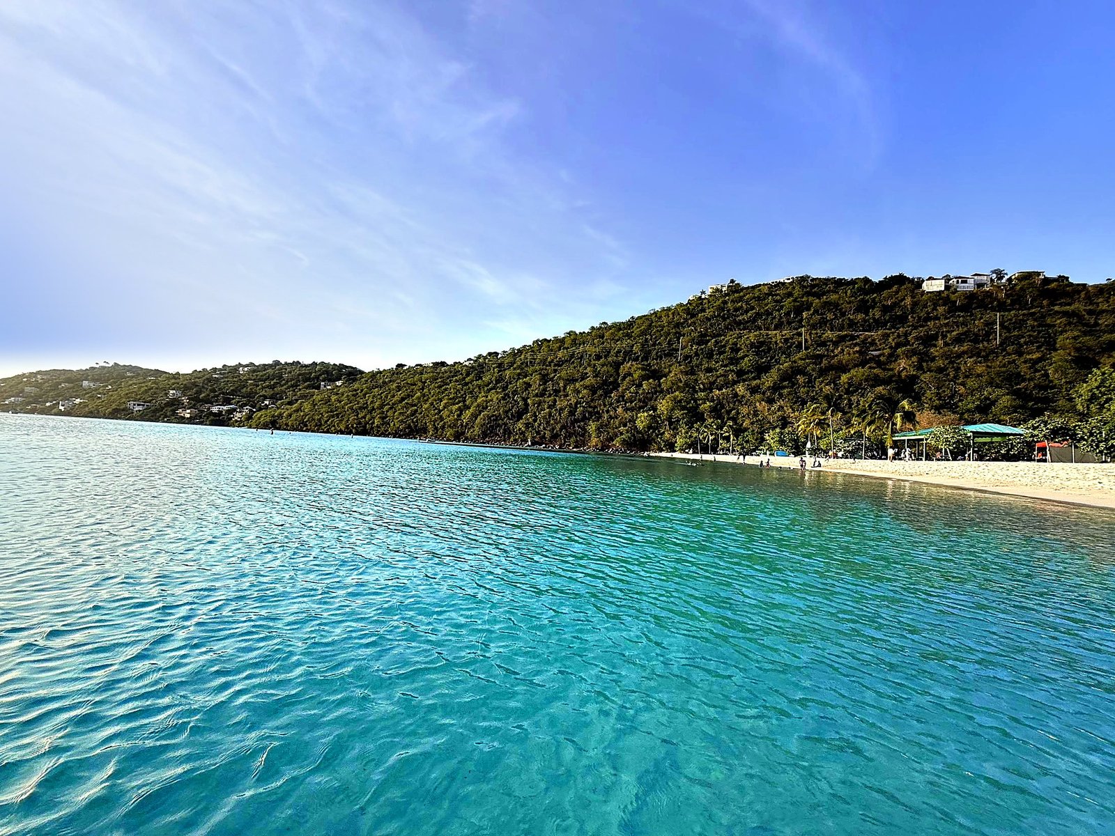 Turquoise bay and white-sand beach below a forested hillside in the US Virgin Islands
