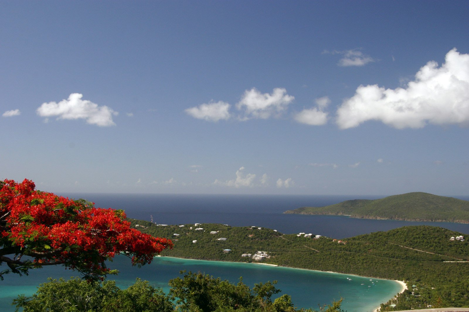 A calm white-sand beach framed by green hills on St. Thomas