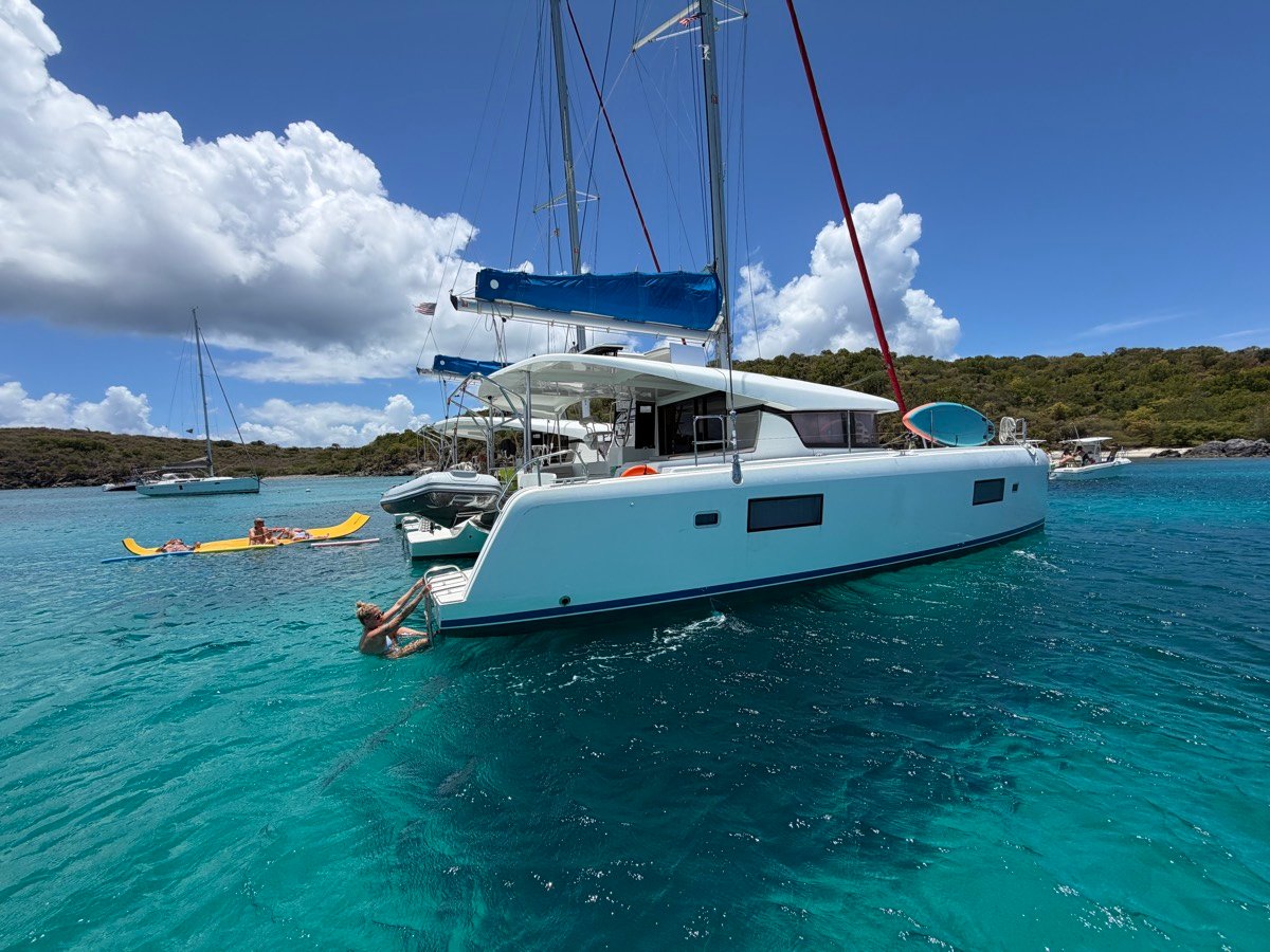 Kai Lana, a Lagoon 42 catamaran, anchored in a turquoise Virgin Islands cove with guests swimming
