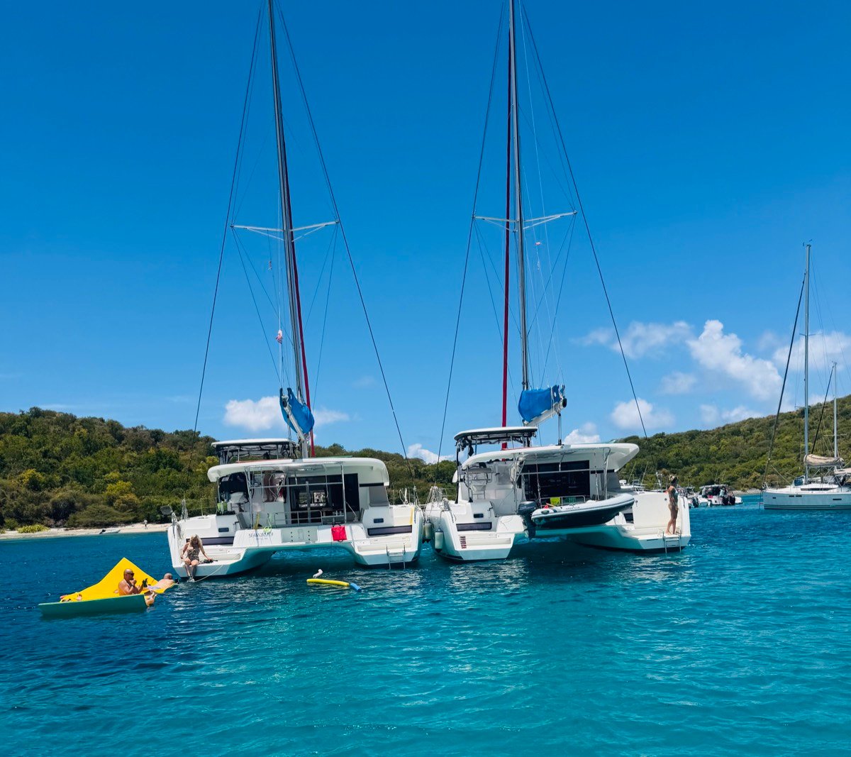 Pau Hana rafted alongside its sister Lagoon 42 catamaran at anchor, guests on a float