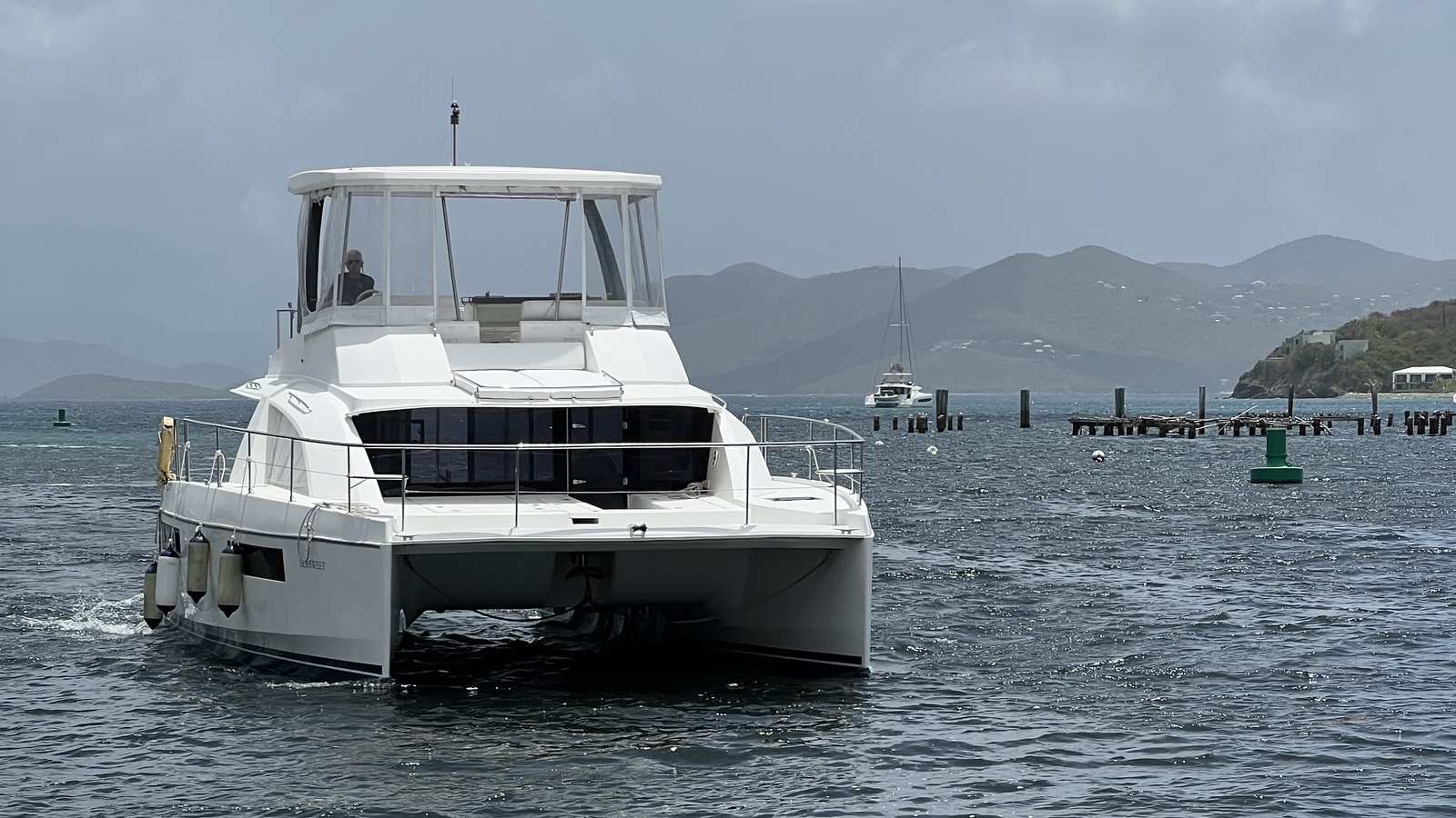 Sea Sweet, a 43-foot Leopard powercat, under way off St. Thomas with her captain at the flybridge helm and the island hills behind